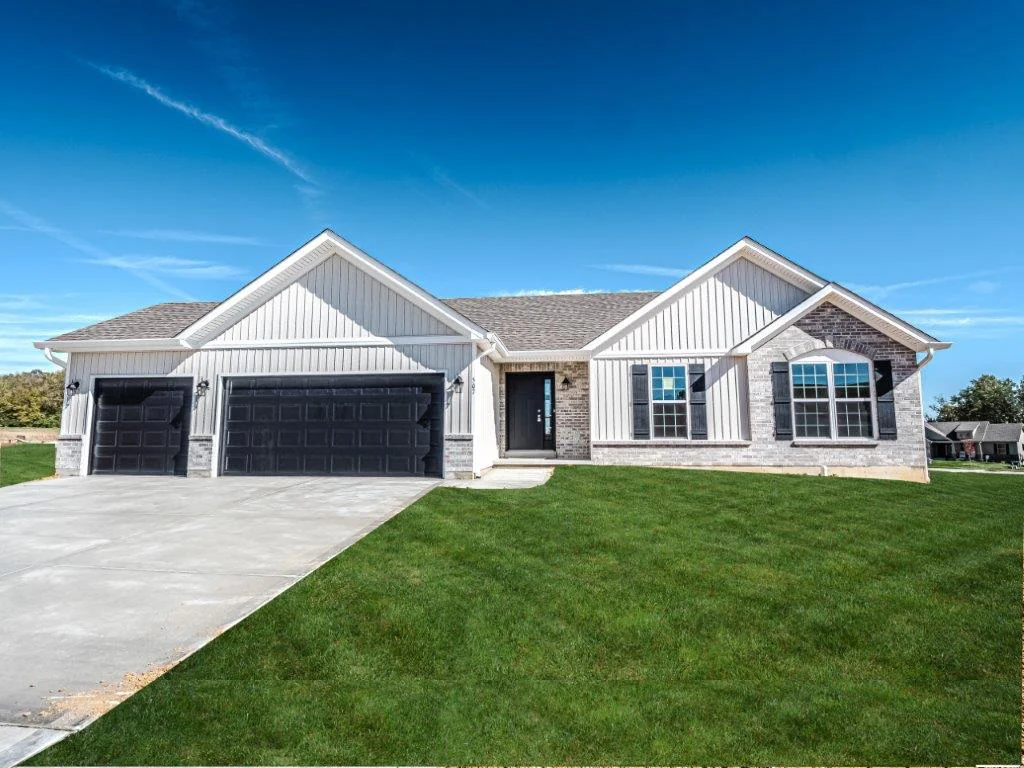 CMS Home plan: white farmhouse-style home with brick and stone, 3-car garage with black garage doors, paned windows, and green, lush grass.